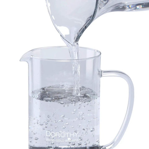 Dorothy Electric Rapid Cold Brewer pitcher with water being poured, showcasing use for home coffee making with Tornado Stir Technology.