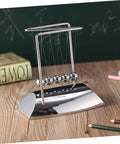 Z Shape Newton Cradle Pendulum Desk Toy For Home Office Decor with five silver balls on a wooden table, educational model.
