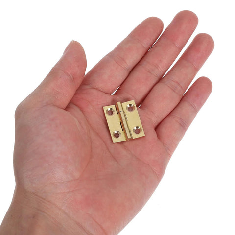 Close-up of FOYTOKI brass foldable cabinet hinge held in hand; small door hardware with four screw holes.