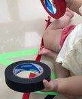 Child holding black painter tape 1 inch by 60 yards, medium adhesive masking tape for painting, labeling, DIY crafts, and more.