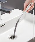 Heavy Duty Drain Cleaning Brush To Kick Stubborn Clogs To The Curb Flexible Pipe Snake Tool in use over a sink.