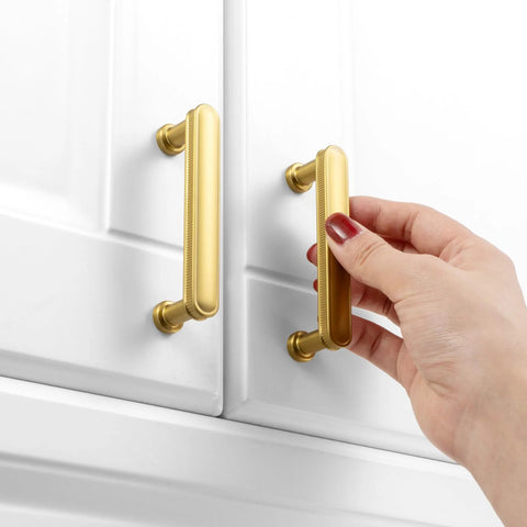 Installing 3 Inch Brushed Gold Cabinet Handles Set on white cabinet, showing rounded edges, solid metal hardware, and smooth finish.