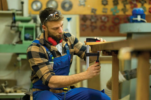 Craftsman using F Style Woodworking Clamp With 2K Handle And Replaceable Pads, for wood assembly in workshop