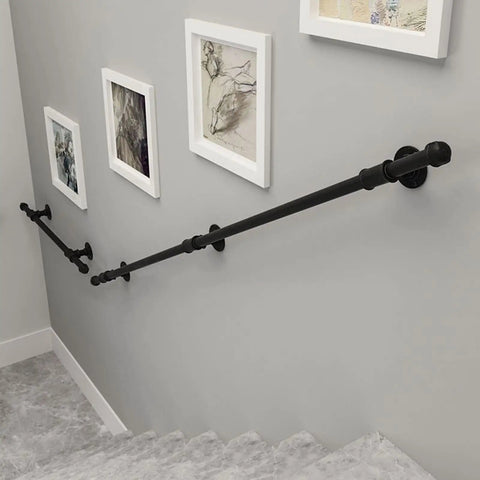 Black Wrought Iron Stair Handrail Wall Mounted Indoor Outdoor Support Bar With Kickass Ergonomic Grip Built Tough For Daily Use Senior Safety Adjustable Length Weather Resistant installed alongside artwork on a gray wall.