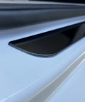 Close-up view of Badass Level Stainless Steel Door Sill Scuff Plate Guards for Rivian R1S R1T R2 on a white vehicle.
