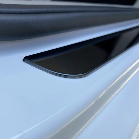 Close-up view of Badass Level Stainless Steel Door Sill Scuff Plate Guards for Rivian R1S R1T R2 on a white vehicle.