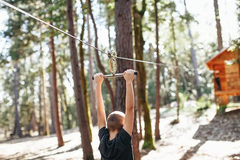 Child using Torpedo Zip Line Trolley With 14 Inch Handlebar And Oval Carabiner For Teens Stainless Steel Dual Ball Bearing Wheels in backyard.