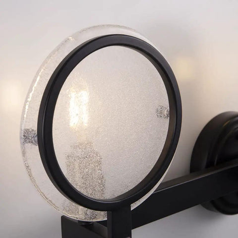 Close-up of Three Light Vanity Light Fixture In Black Gold Finish With Seeded Glass Over Mirror Wall Sconces