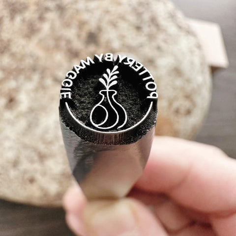 Close-up of Pro Grade Metal Signature Stamp For Jewelry And Metalwork showing crisp imprint of logo on stainless steel surface.