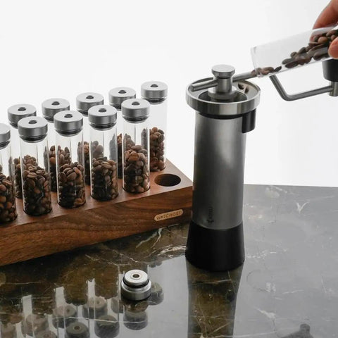 12 Piece Single Dose Coffee Bean Storage Tubes With One Way Exhaust Valve Glass Vials On Sturdy Walnut Wood Base And Easy Pouring Funnel with coffee beans in tubes.