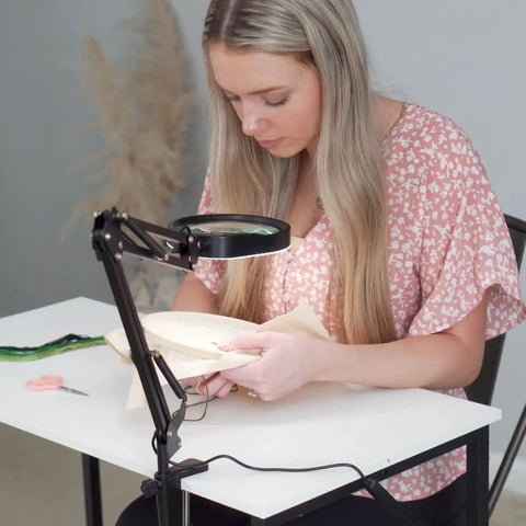 Woman using 10X Magnifying Desk Lamp With 96 LEDs for detailed embroidery, adjustable swivel arm, 5-inch real glass lens on desk