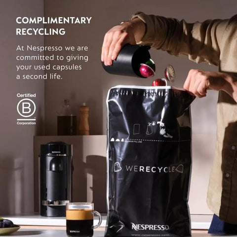 Person recycling used Nespresso capsules into a black recycling bag with coffee maker and mug on the counter