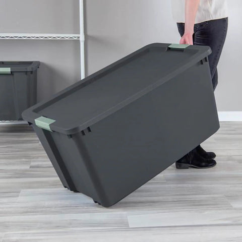 Person carrying Hella Tough 12 Pack 45 Gallon Wheeled Latch Tote plastic storage bin with smooth rolling wheels indoors.