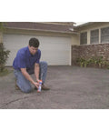 Man applying Premium Elastomeric Blacktop Driveway Crack Repair For Cracks In Asphalt Surfaces Ideal For Driveways Walks And Parking Lots