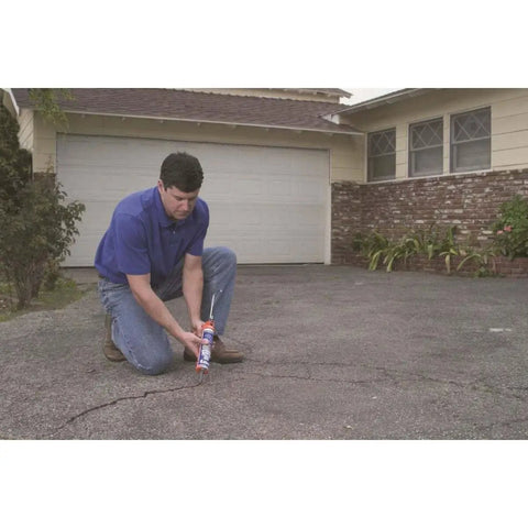 Man applying Premium Elastomeric Blacktop Driveway Crack Repair For Cracks In Asphalt Surfaces Ideal For Driveways Walks And Parking Lots