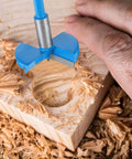 Blue 48mm woodworking hole saw drill bit with hex handle drilling into wood.