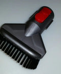V8 Cordless Vacuum Tool Kit With Mattress Attachment, featuring black bristles, red latch, for upholstery cleaning.