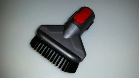 V8 Cordless Vacuum Tool Kit With Mattress Attachment, featuring black bristles, red latch, for upholstery cleaning.