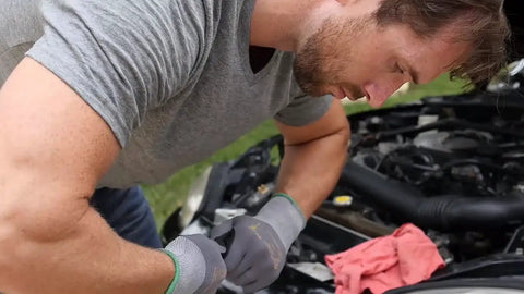 Man wearing Maxiflex PIP Large Ultimate Micro Foam Nitrile Coated Work Gloves with Nylon Liner, working on car engine.
