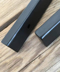 Close-up of Heavy Duty Wall Mounted L Shape Shelf Brackets Two Pack Slick Black Finish Rust Proof Steel on wood surface.