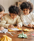 Children crafting with paper and handheld one quarter inch single hole paper punch with built in mess free waste tray.