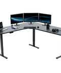 Rock Solid Corner Standing Desk Rig In Matte Black With Lightning Fast Height Adjustments And Split Tabletop Design set up with dual monitors and laptop.