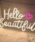Hello Beautiful Neon Sign For Girl's Room Wall Decor With Dimmer Switch Romantic Neon Light For Weddings Valentine's Day Parties Gifts 12V Warm White With Power Adapter Included glowing on a table.
