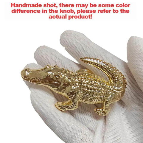 Gloved hand holding gold crocodile-shaped cabinet knob from Crocodile Shaped Cabinet Knobs Set Of 4 In Zinc Alloy Decorative Drawer Pulls For Dresser Cabinet And Closet Vintage Gold Hardware With Single Hole Mount And Rust Resistant Animal Handles.