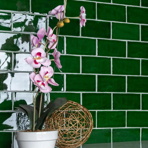 Viva Antic Verde 3x6 Ceramic Wall Tile With Dope Glazed High Sheen Finish behind a pink orchid in a pot
