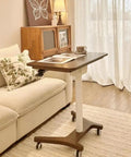 No Drama Roll Mobile Standing Desk Featuring Smooth Gas Lift Adjustments And A Tilt Tray Top Portable Laptop Desk next to couch with decorative pillow.