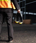 Person holding Turbotoe TTXXL Steel Toe Overshoe Green M13-14 For Job Sites in one hand at a construction site.