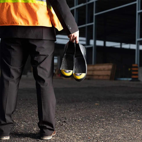 Person holding molded safety steel toe caps for worksite toe protection with durable impact resistant design, XS size.