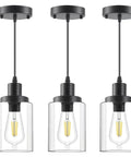 Three Pack Black Industrial Pendant Lights With Clear Glass Shades hanging from ceiling with adjustable cords, modern design.