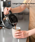 Fresh Ground Bean To Cup Drip Coffee Maker With Built In Auto Grinder pouring coffee into a cup from a glass carafe.