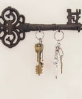 Brown Cast Iron Skeleton Key Wall Hook With Three Heavy Duty Coat Holders For Classic Farmhouse Vibes And Simple Down Home Entryway Organization Built Rock Solid For Everyday Hanging with keys and bags.