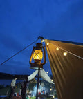 Bronze Outdoor LED Lantern With Vintage Flame Effect glowing at night on a campsite for garden and patio decor