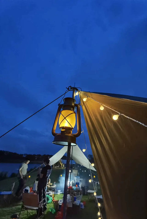 Bronze Outdoor LED Lantern With Vintage Flame Effect glowing at night on a campsite for garden and patio decor
