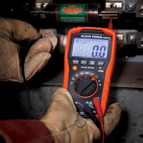 Digital Auto Ranging Multimeter For AC DC Voltage And Current With Temperature Frequency Capacitance Duty Cycle Diode And Continuity Tests 1000V CAT IV 600V CAT III 1000V Safety Built Tough And Drop Ready Orange in use by technician.
