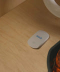 Smart WiFi Water And Freeze Detector With 80dB Audible Alarm Text And Email Alerts Continuous Home And Investment Property Monitoring Two Year Battery Life With Replaceable AAA Batteries placed under kitchen sink