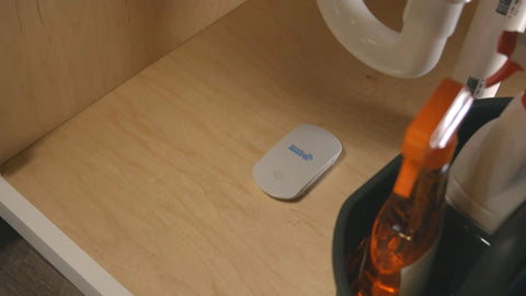 Smart WiFi Water And Freeze Detector With 80dB Audible Alarm Text And Email Alerts Continuous Home And Investment Property Monitoring Two Year Battery Life With Replaceable AAA Batteries placed under kitchen sink