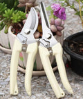 Must Have Grab And Go Garden Shears Set Of 2 With Bypass Pruning Shears And Straight Blade Garden Scissors Ultra Lightweight And Sharp Easy Grip For Live Plants Flowers Stems Vines Roses And Twigs, shown with ivory handles next to potted plants