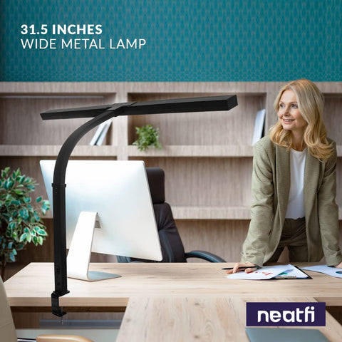 Boss Level LED Desk Lamp With Clamp, 31.5-inch arm, modern office setting, woman stands near desk, sleek black design