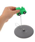 Hand holding a green train toy above TEHAUX Silicone Bathtub Drain Stopper 15cm, Hair Catcher for Bathroom.
