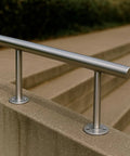 2-inch OD stainless steel tubing with brushed finish, mounted on round flange posts along concrete steps.