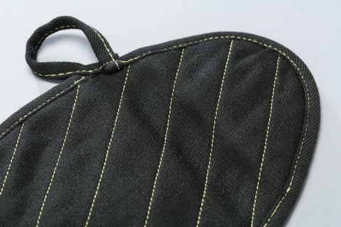 Close-up of X Pad Suppressor Handler in black with DuPont Kevlar stitching, CarbonX heat resistance up to 2000°F for tactical duty gear.