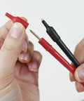Hands holding red and black gold-plated tip leads for Card Size HiTester And Digital Multimeter With 41.99 Megaohms Resistance 500 Volts AC DC Range Auto Ranging And Auto Power Save Overload Protection Up To 500 Volts Palm Sized And Lightweight With Gold Plated Tip Leads With 15Mm Pin Length.