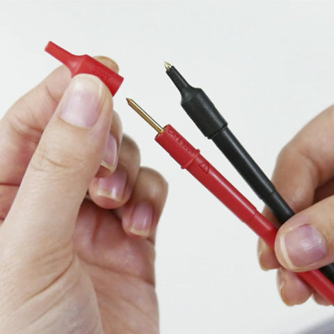 Hands holding red and black gold-plated tip leads for Card Size HiTester And Digital Multimeter With 41.99 Megaohms Resistance 500 Volts AC DC Range Auto Ranging And Auto Power Save Overload Protection Up To 500 Volts Palm Sized And Lightweight With Gold Plated Tip Leads With 15Mm Pin Length.
