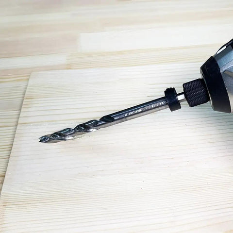 One Quarter Inch Hex Shank Pocket Hole Drill Bit With Depth Stop Collar installed in a drill for woodworking on a board