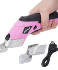 3.7V Cordless Electric Scissors Fast Cutting Fabric Cutter For Carpets Cardboard Leather With Dual Blades And Charging Cable Perfect DIY Sewing Tool Lightweight Handheld Design Easy To Use Powerhouse Pink held in hand with replacement blade and charging cable.