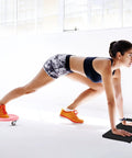 Woman using Four Wheel Ab Roller Exercise Wheel with Knee Mat for indoor core workout in bright workout space.